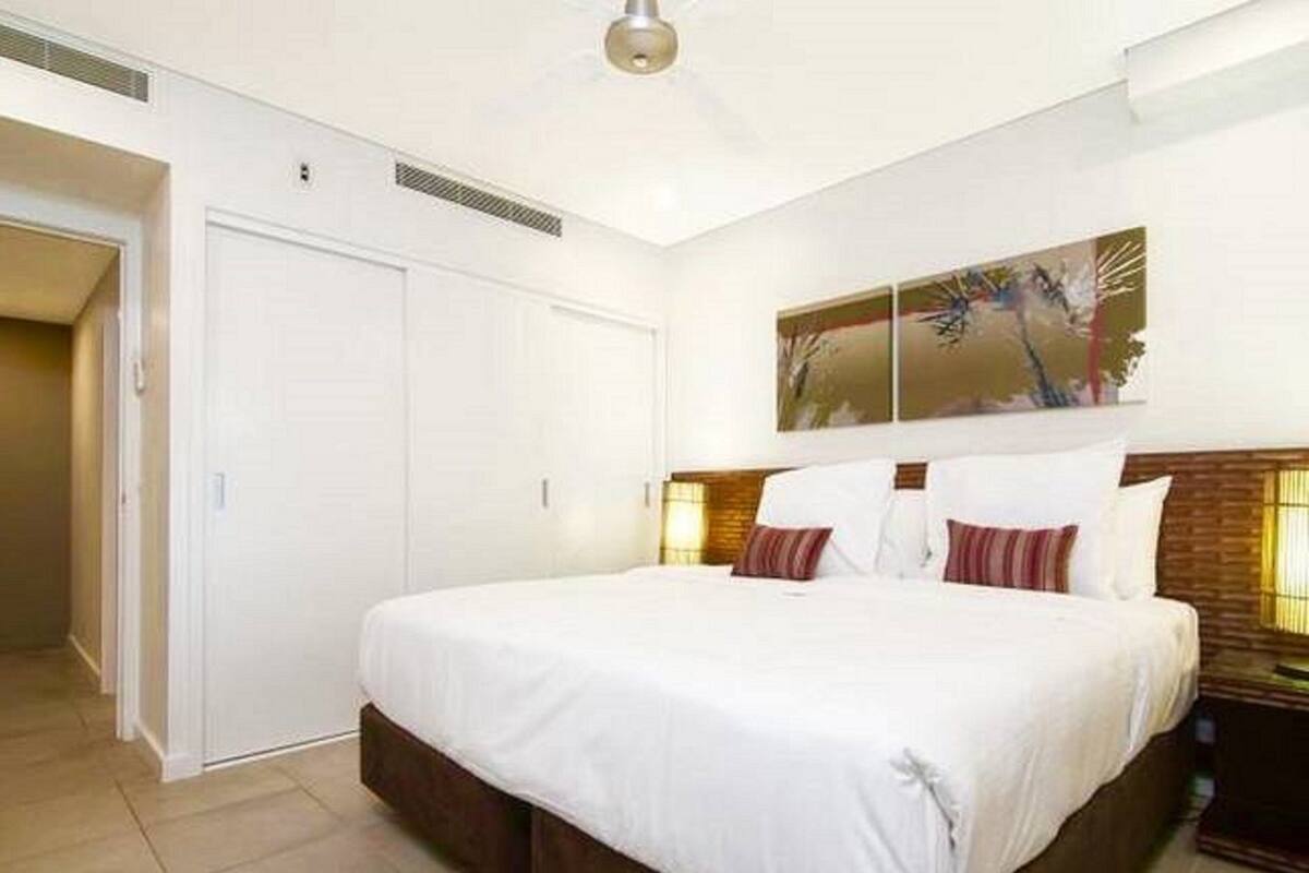 A bedroom with a large bed, a wardrobe, and a painting on the wall.
