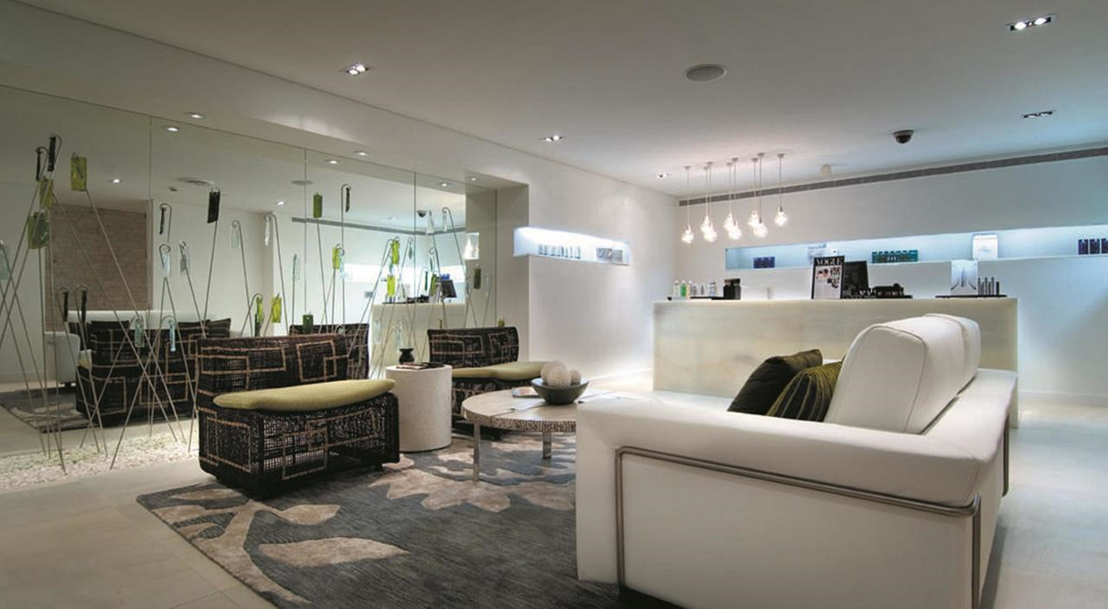 A modern hotel lobby with a reception desk, seating area with sofas and a coffee table, and a patterned rug.