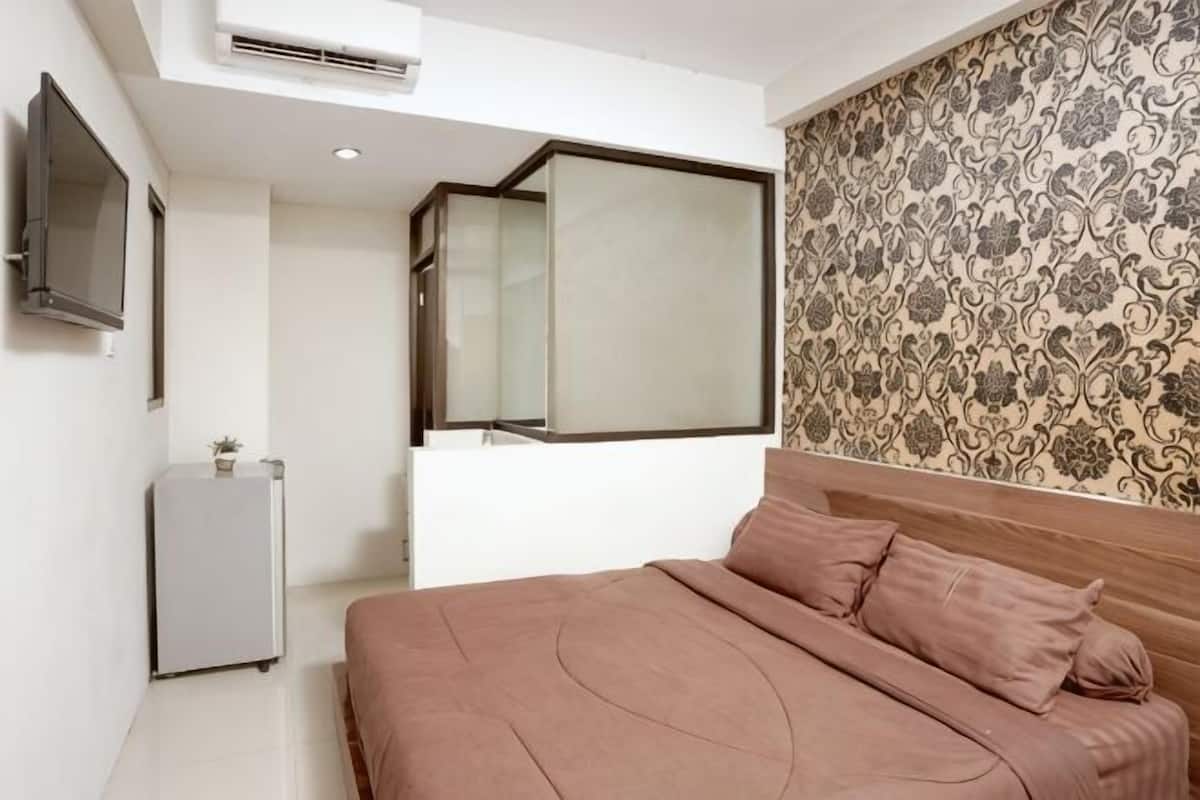 A bedroom with a bed, a TV, a small table, and a mirror.