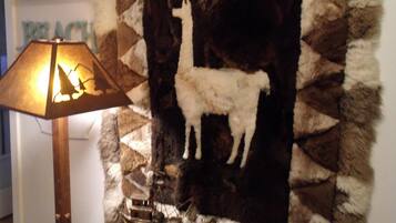 A room with a lamp, a wall hanging of a llama, and a ship model.
