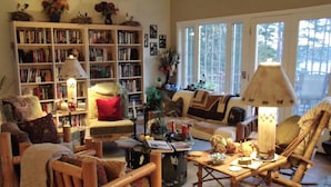 A cozy living room with a bookshelf, a sofa, a coffee table, and a chair.