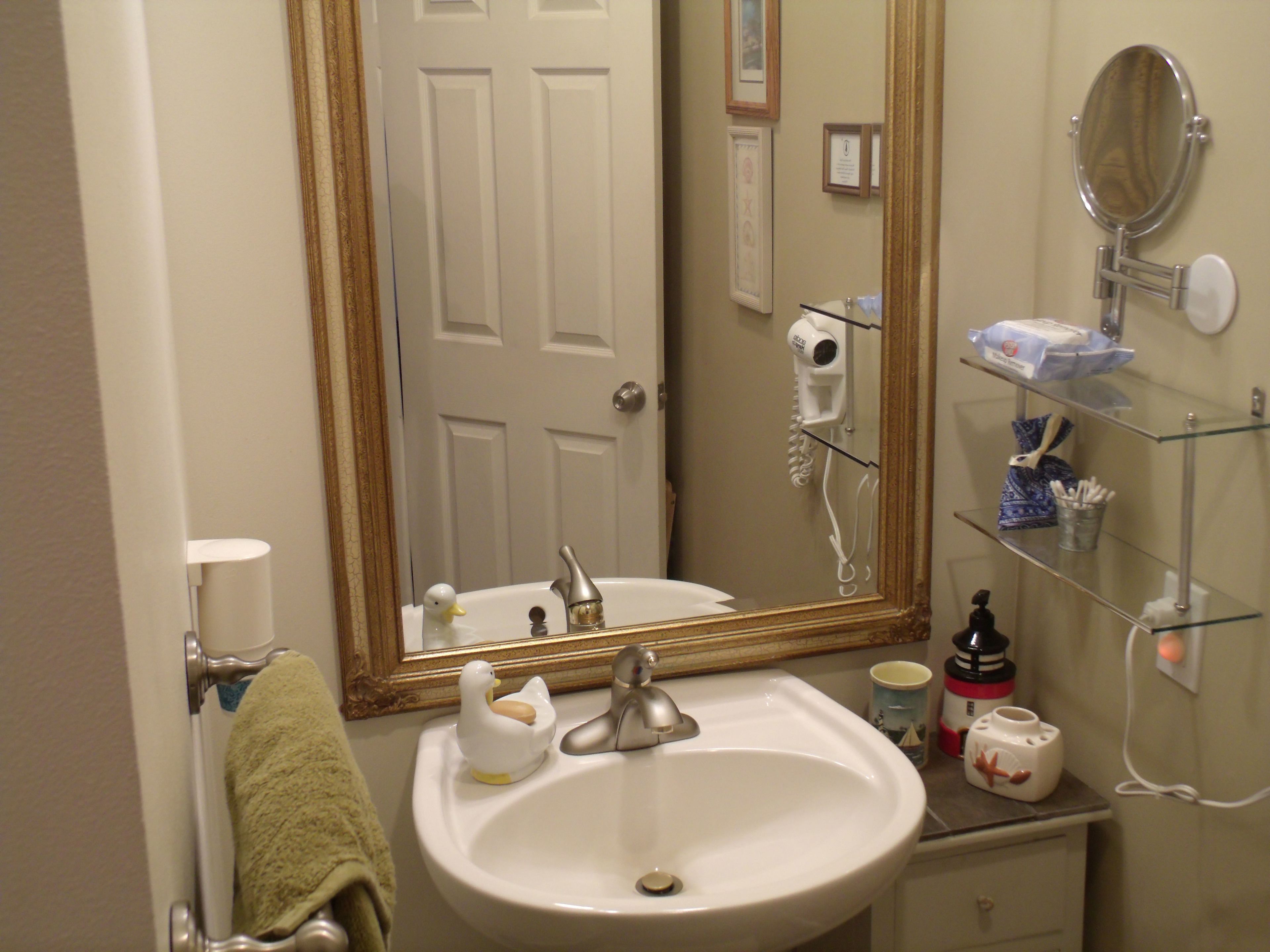 A bathroom with a white sink, a mirror, a hairdryer, and a shelf with toiletries.