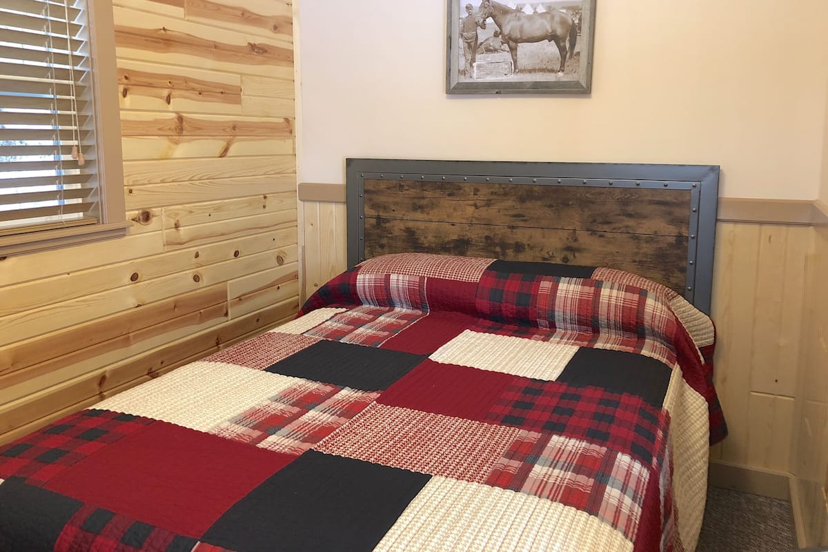 Une chambre à coucher avec une tête de lit en bois, une couvre-lit matelassée et un tableau encadré accroché au mur.