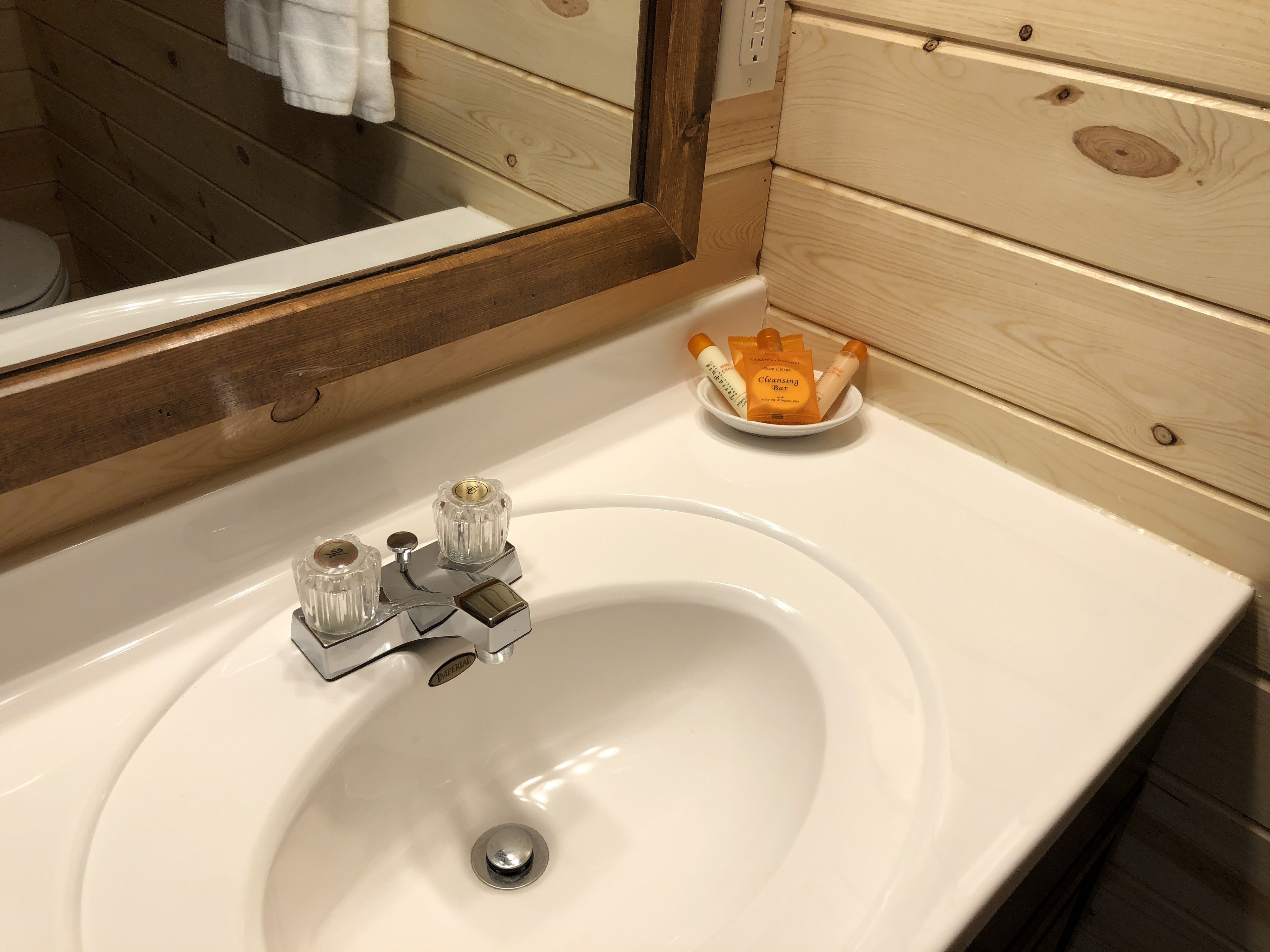 A bathroom with a white sink, a mirror, and a small bowl of toiletries.