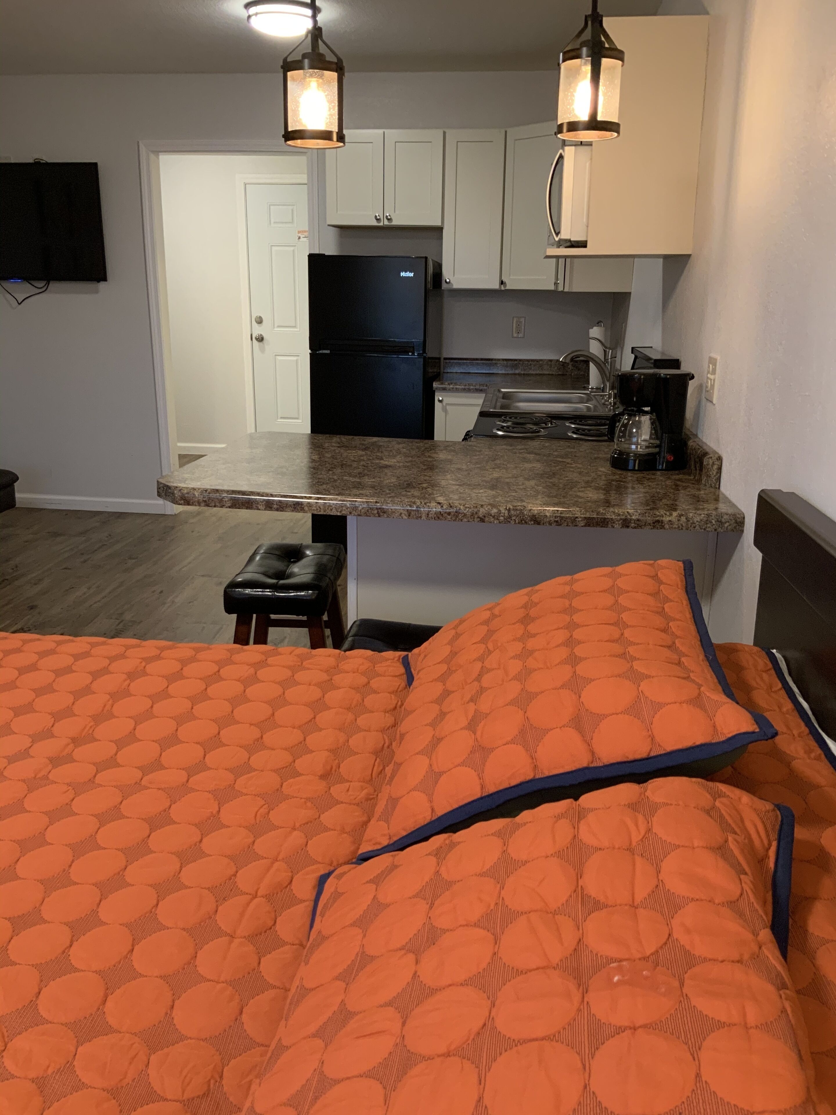 A compact kitchen with a refrigerator, stove, and coffee maker.