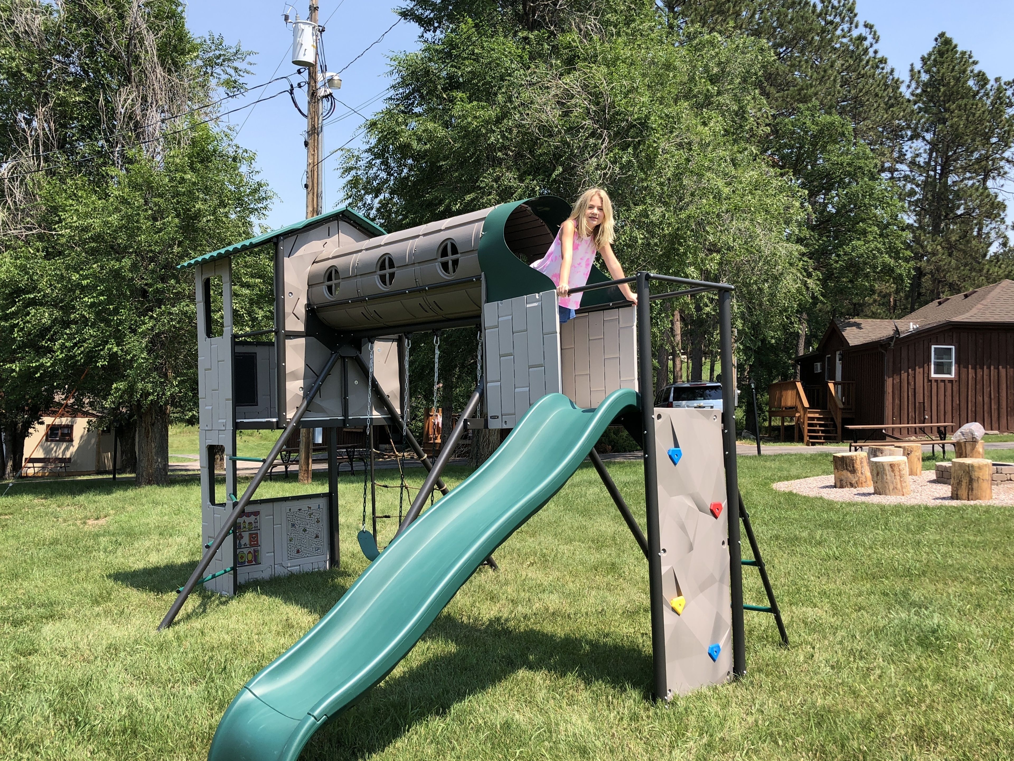 A playground with a slide, climbing wall, and a covered playhouse.