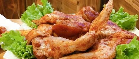 A plate of cooked chicken wings with lettuce leaves.