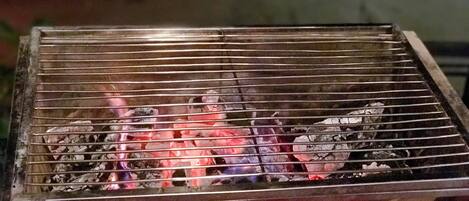 Una parrilla con carbón a la vista y llamas.