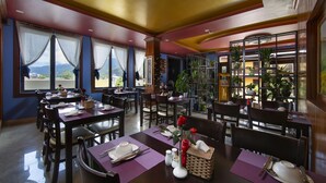 A restaurant with tables set for dining, chairs, and a large window with curtains. - Sapa Sweet Time Hotel (Sa Pa)