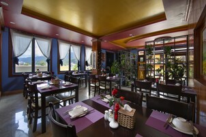 A restaurant with tables set for dining, chairs, and a large window with curtains.