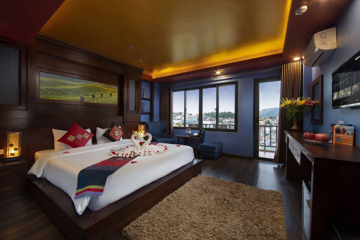 Una habitación de hotel moderna con una cama grande, vistas a la ciudad y un balcón.