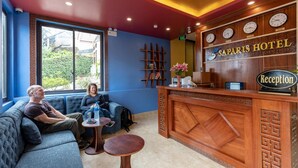 A reception area with a wooden reception desk, a blue wall, and a large window. - Sapa Sweet Time Hotel (Sa Pa)