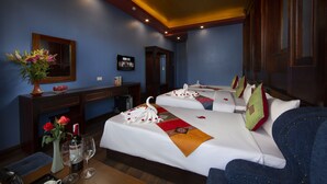 A hotel room with two beds, a desk, a TV, and a vase with flowers. - Sapa Sweet Time Hotel (Sa Pa)