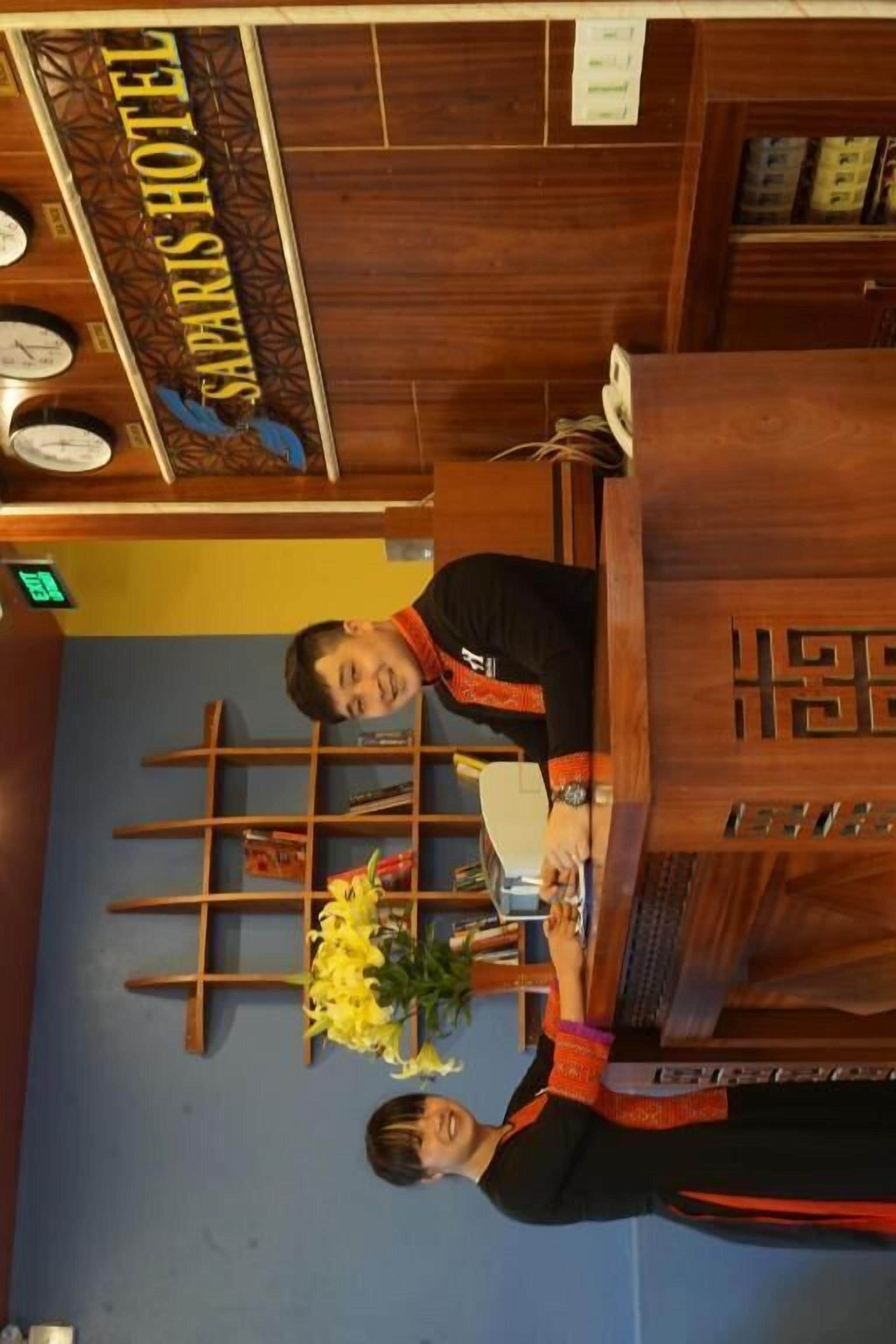 A reception desk with a wooden counter, a nameplate, and a wall-mounted clock.