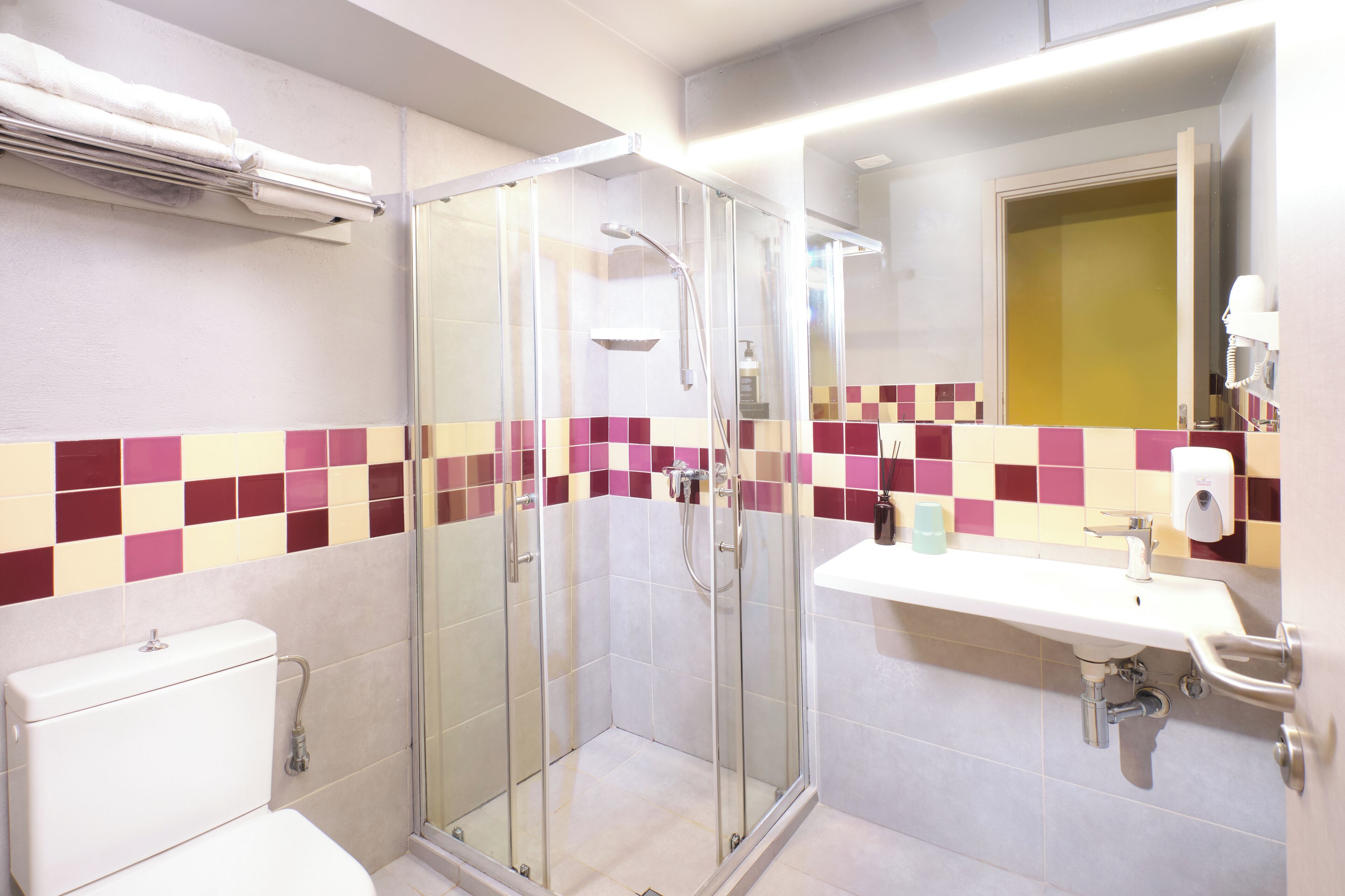 A bathroom with a glass-enclosed shower, a toilet, and a sink with a mirror above it.