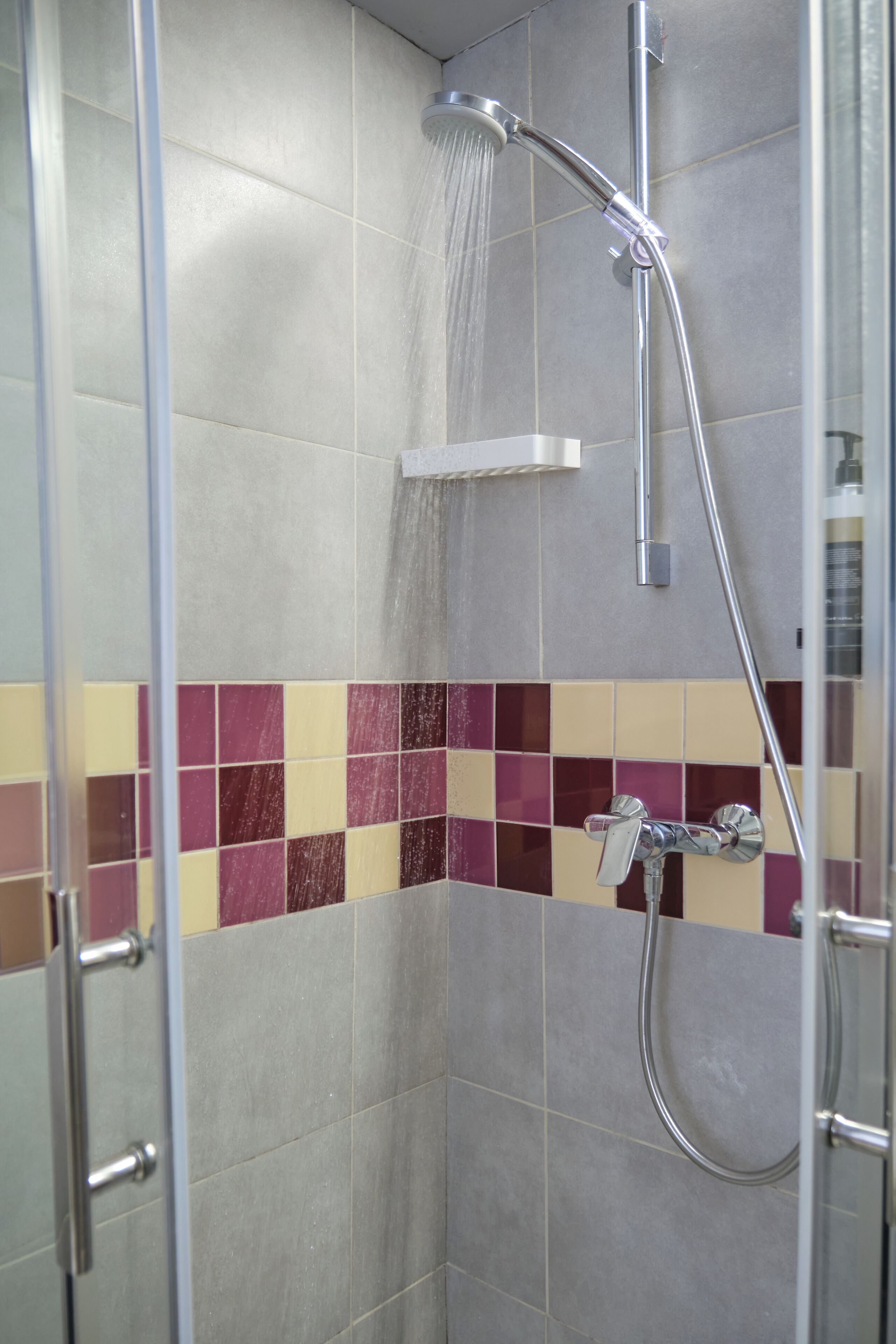 A shower with a handheld showerhead and a wall-mounted faucet.