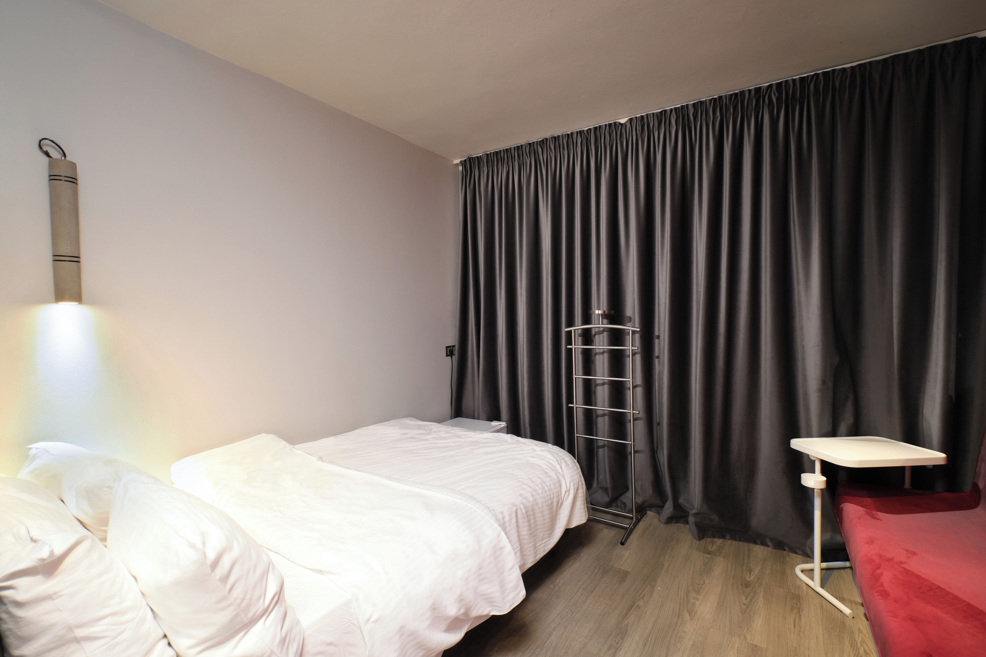 A hotel room with two beds, a desk, a chair, a ladder, and a curtain.