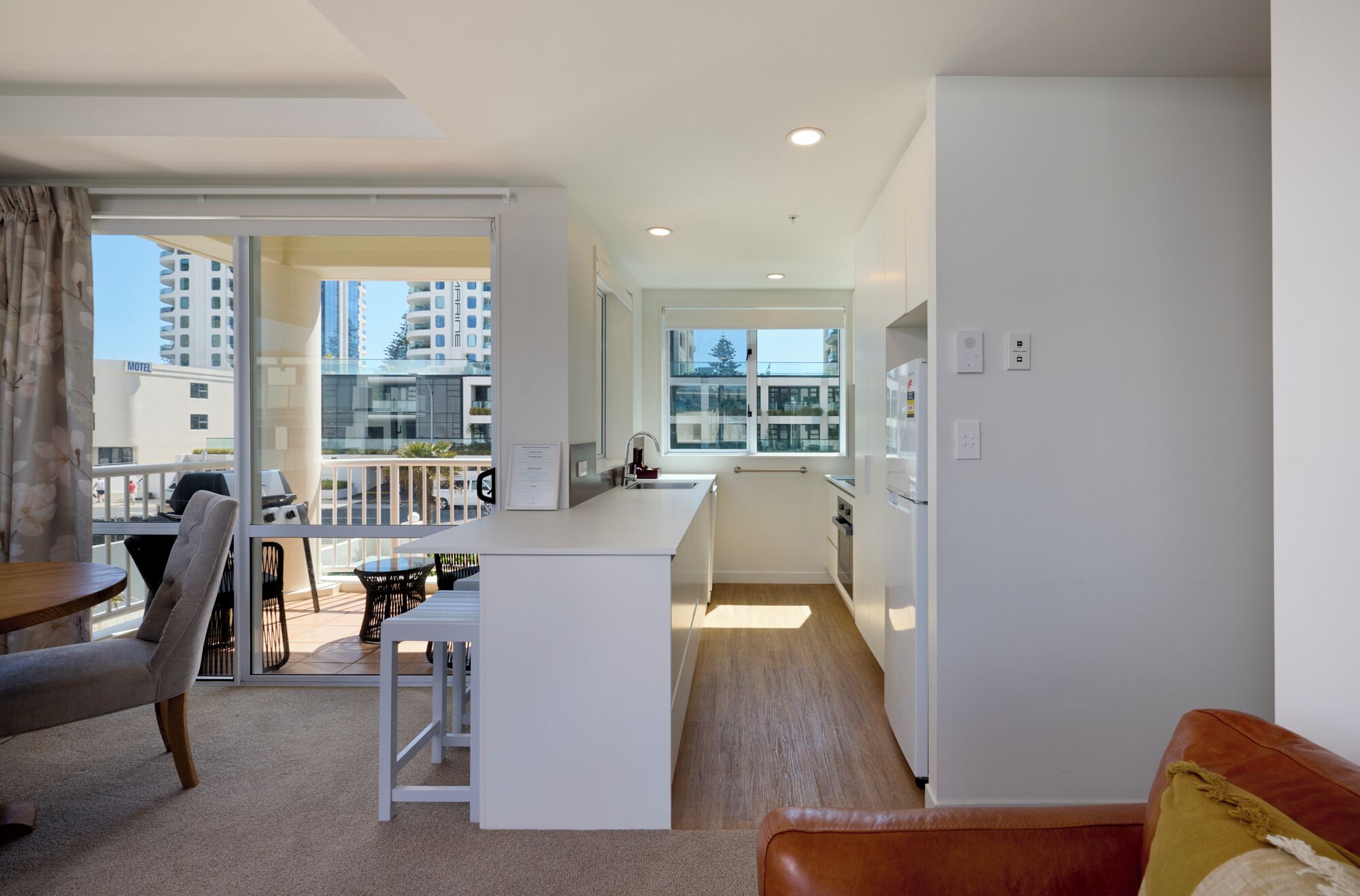 A modern apartment with a balcony, a kitchenette, and a dining area.