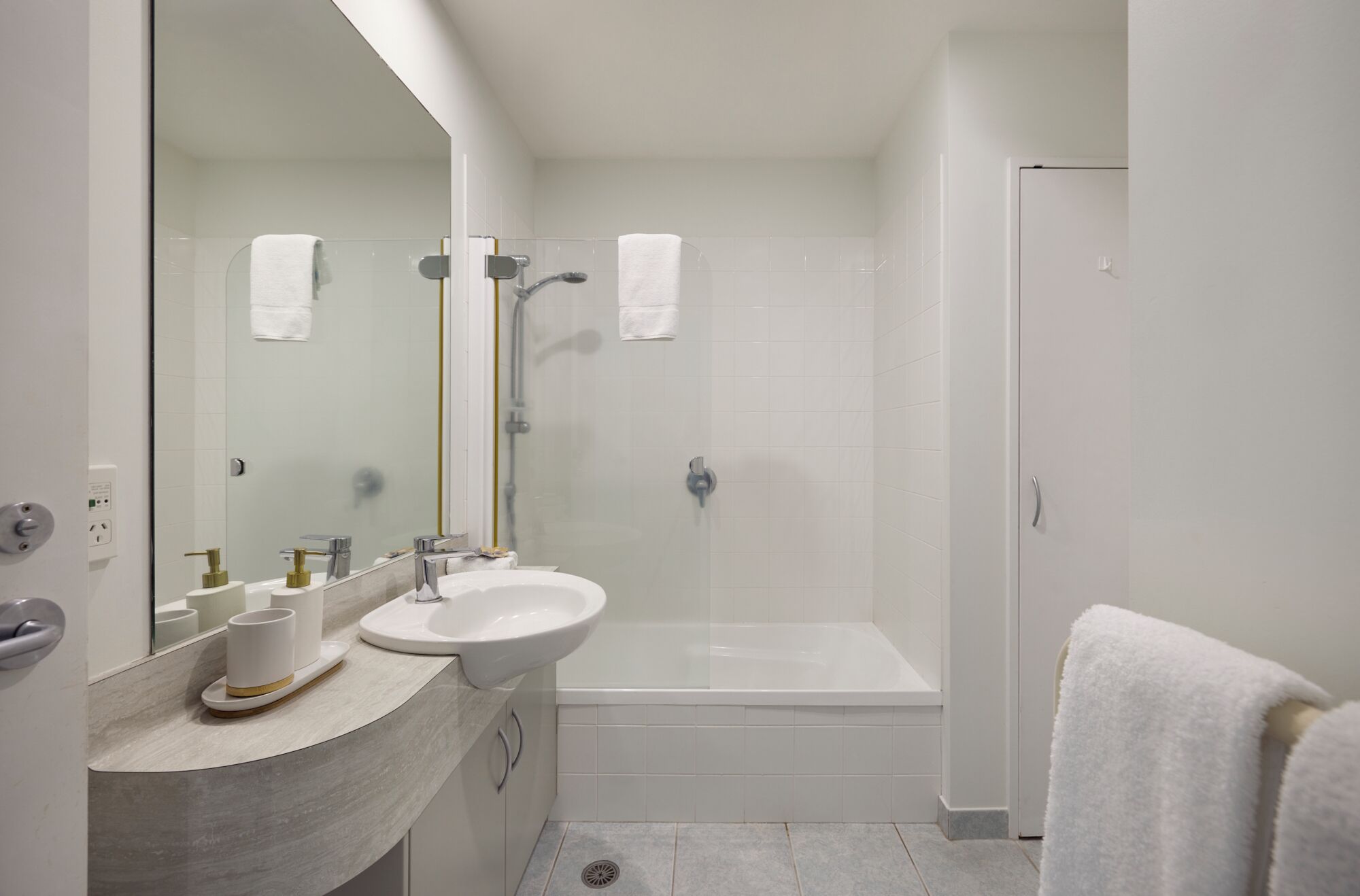 A bathroom with a sink, mirror, shower, and toilet.
