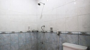 A small, tiled shower area with a toilet, a handheld showerhead, and a wall-mounted faucet. - Warapsari Inn (Kuta)