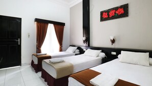 A hotel room with three beds, a large window with brown curtains, a wall-mounted artwork, and a door. - Warapsari Inn (Kuta)