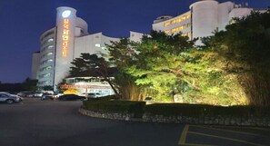 Un hotel moderno con una torre destacada y un estacionamiento.