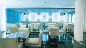 A modern hotel lobby with round tables and chairs, a glass partition wall, and a blue accent wall. - Seorak Pine Resort (Sokcho)