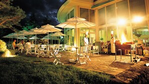 An outdoor dining area with tables and chairs, umbrellas, and a chef preparing food. - Seorak Pine Resort (Sokcho)