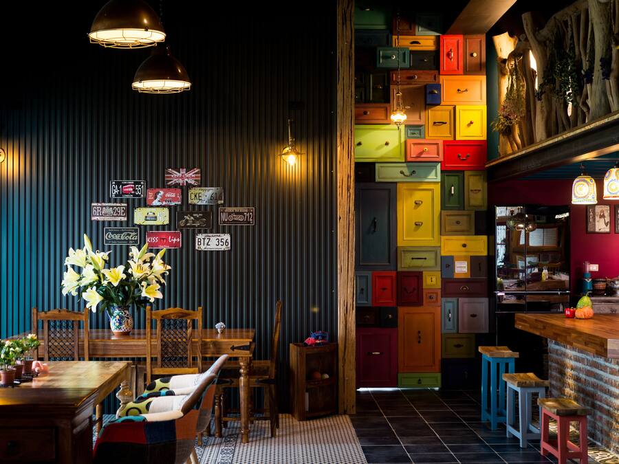 Un restaurant doté d’un bar, de tables et de chaises en bois, ainsi que d’un mur coloré agrémenté de boîtes de rangement.