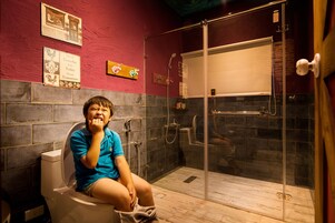 Un baño con ducha, inodoro y un detalle decorativo en la pared.