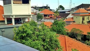 A residential area with red-tiled roofs, a variety of building styles, and lush green vegetation. - Taman Mekar Beach Inn (Kuta)