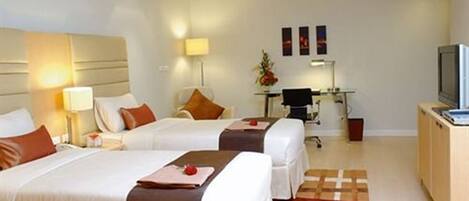 A hotel room with two beds, a desk, a chair, a television, and a small table.