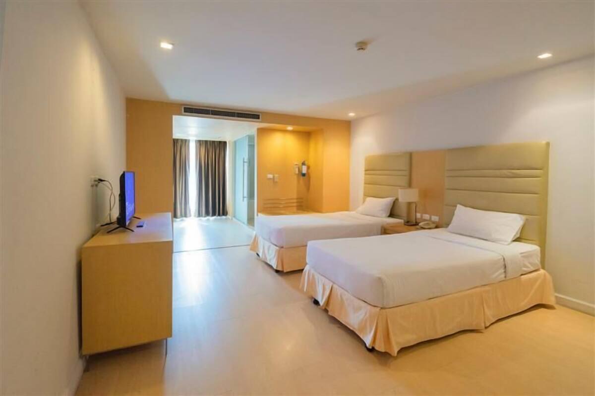 Une chambre d’hôtel avec deux lits, un bureau, une chaise et un téléviseur.