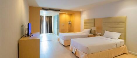 A hotel room with two beds, a desk, a chair, and a television.