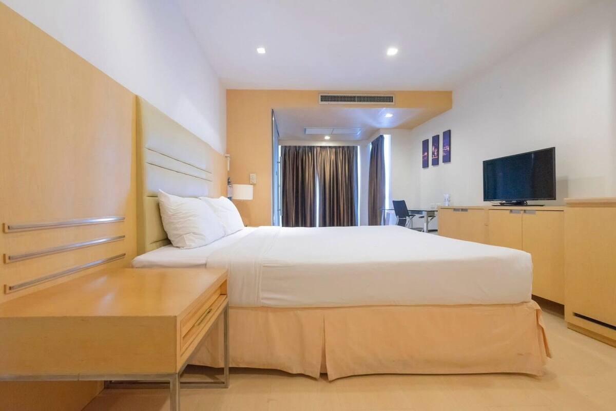 Une chambre d’hôtel équipée d’un lit, d’une table de chevet, d’une télévision et d’un bureau avec une chaise.