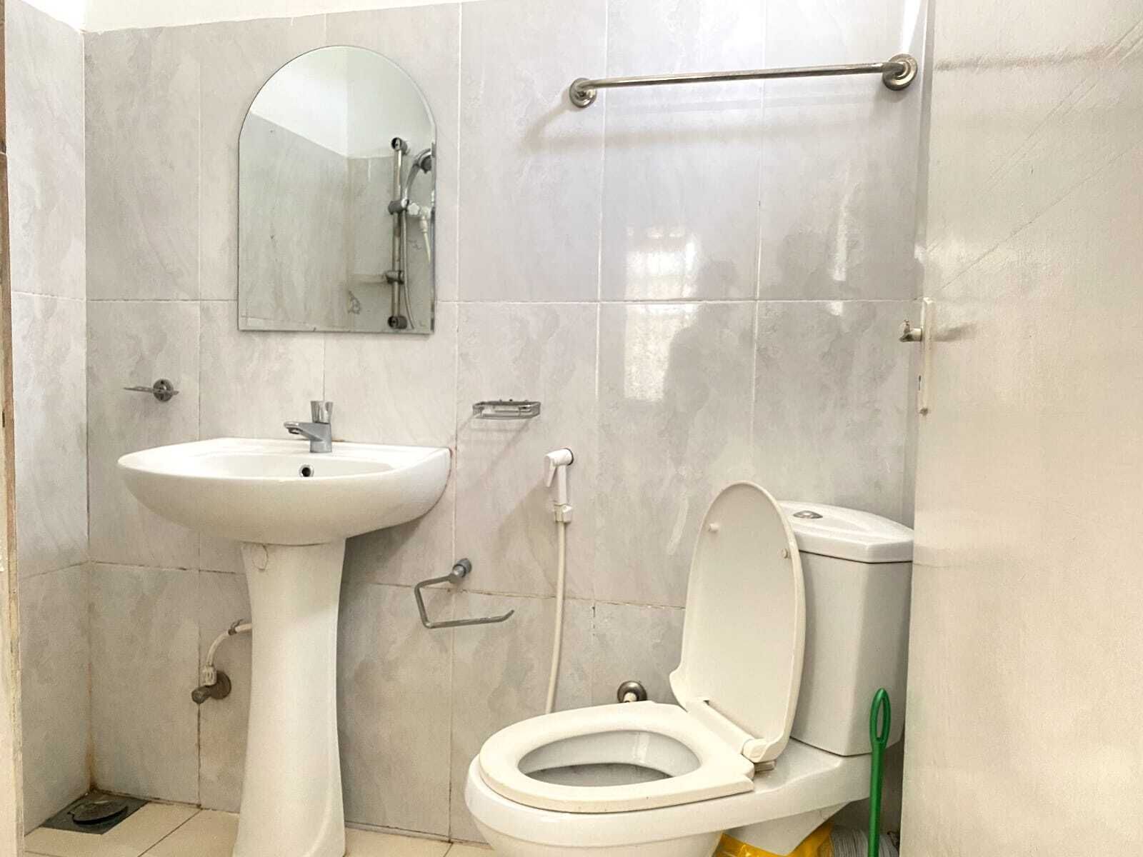 Un baño con lavamanos pedestal, inodoro, espejo y toallero.