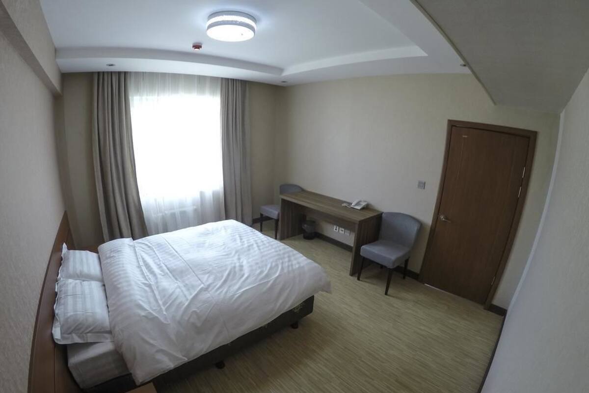 Una habitación de hotel con una cama, un escritorio, una silla y una puerta.