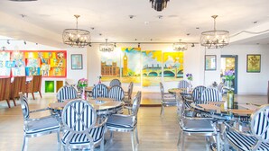 A modern restaurant with striped chairs and tables, art on the walls, and chandeliers. - Mount Bogd Apartment (Ulaanbaatar)