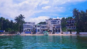A beachfront hotel with multiple buildings, a sandy beach, and boats in the water. - Arkipelago Divers and Beach Resort (Puerto Galera)