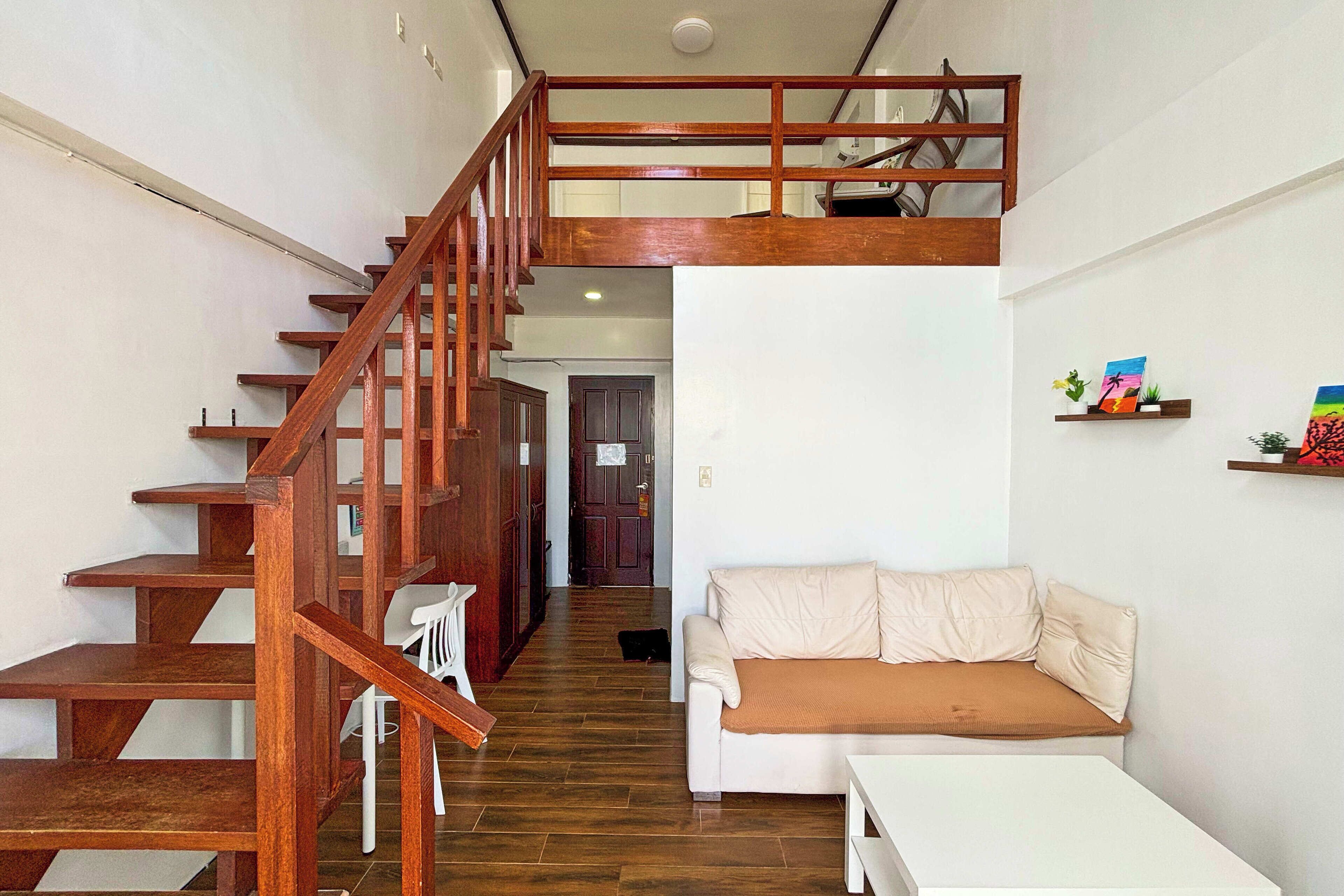 A staircase leading to a loft, a white sofa, and a small table in a modern interior.
