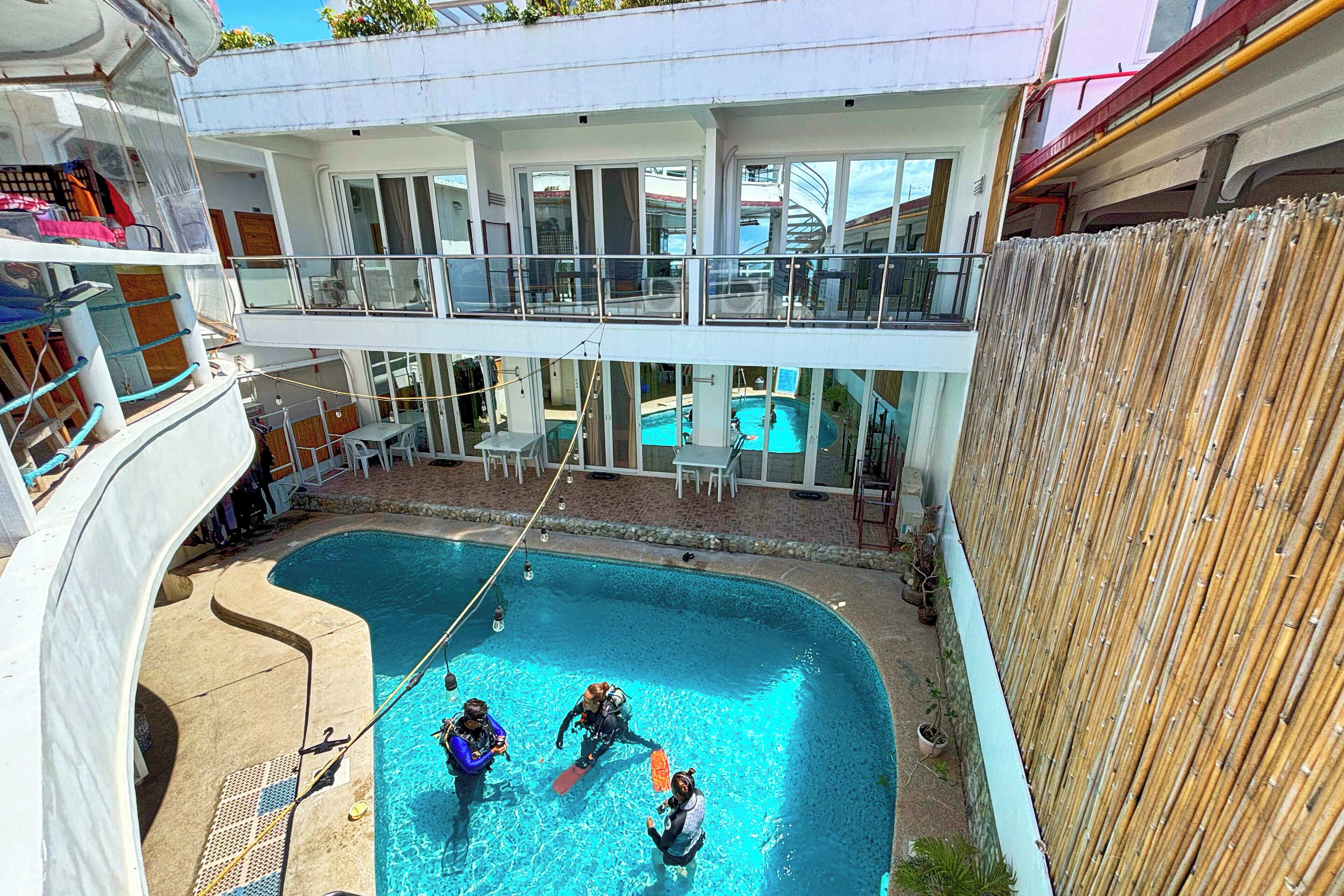 A pool area with three people in the water, a covered seating area, and a view of the ship's deck.