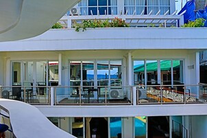 Un edificio de varios niveles con balcones, ventanas amplias y una zona de piscina.