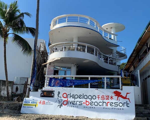 Um edifício com vários andares, com uma placa indicando 'Arkipelago Divers Beach Resort' e 'Tech Asia Divers Institute'.