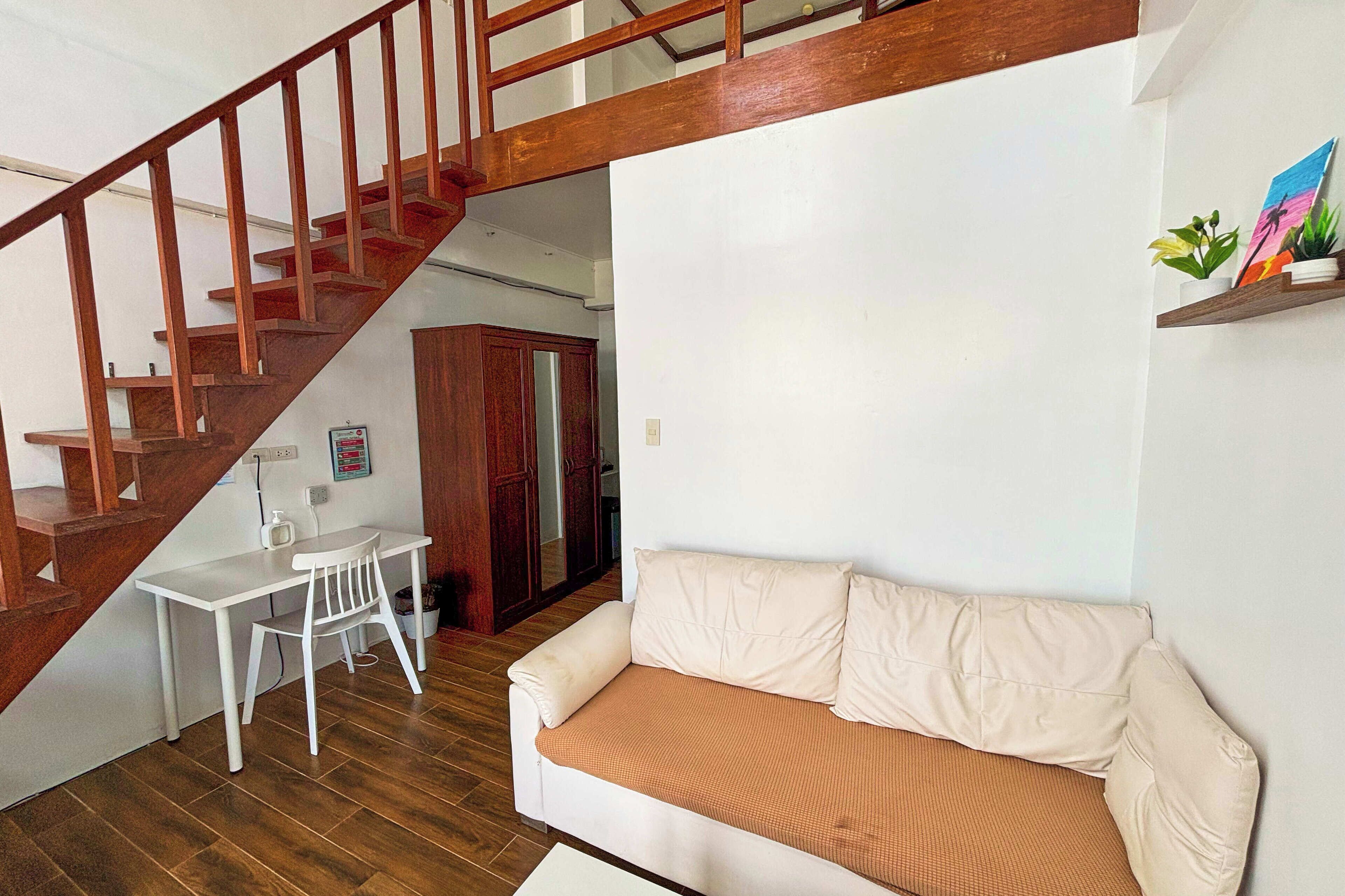 Ein Wohnzimmer mit einem weißen Sofa, einem kleinen weißen Tisch und einer Holztreppe.