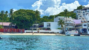 A beachfront hotel with multiple floors, a pool area, and a beach in the background. - Arkipelago Divers and Beach Resort (Puerto Galera)