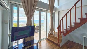 A spacious room with a large sliding glass door leading to a balcony with a view of the sea. - Arkipelago Divers and Beach Resort (Puerto Galera)