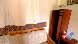 Una stanza con un divano in legno, cuscini decorati, un armadietto in legno e uno specchio.