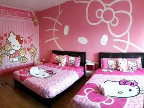 Quarto decorado em tons de rosa, com duas camas, cada uma com roupa e almofadas Hello Kitty.