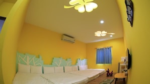Una habitación con una cama grande, un escritorio y una silla. Hay una ventana con cortinas, un equipo de aire acondicionado en la pared y un televisor montado en la pared.