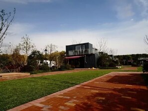 A modern building with a flat roof, surrounded by a well-maintained lawn and brick pathway. - Lin Jia Camping Site Shanghai (Shanghai)